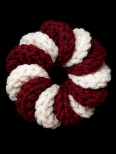 Handmade crochet ring in red and white yarn, circular jewelry accessory.