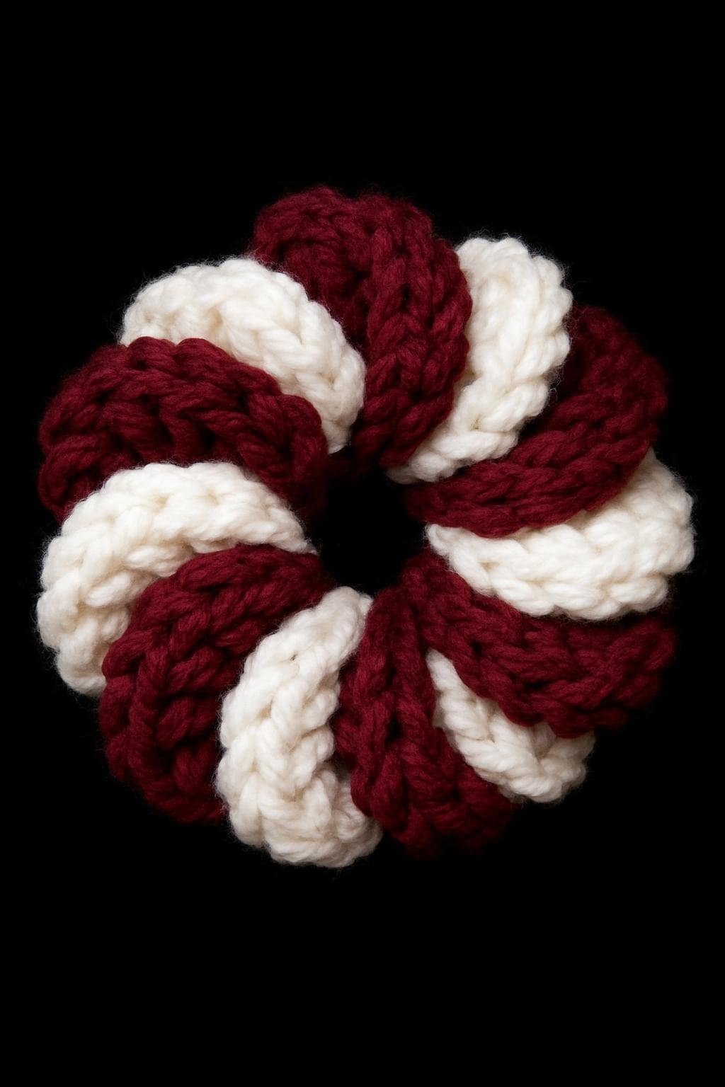 Handmade crochet ring in red and white yarn, circular jewelry accessory.